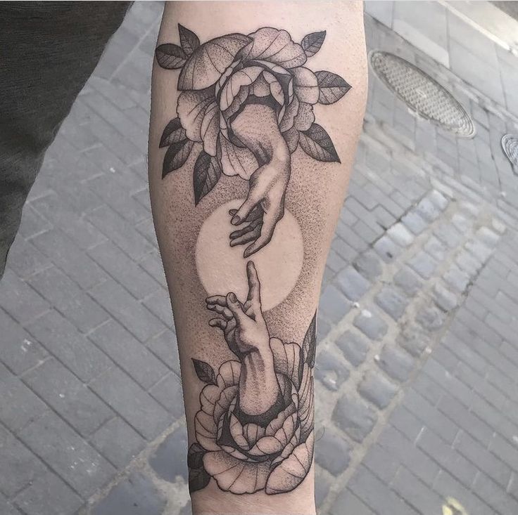 a woman's leg with a tattoo on it that has flowers and hands holding each other