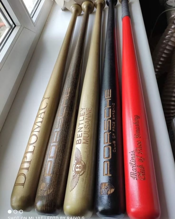 baseball bats lined up in a row on a window sill next to a bat