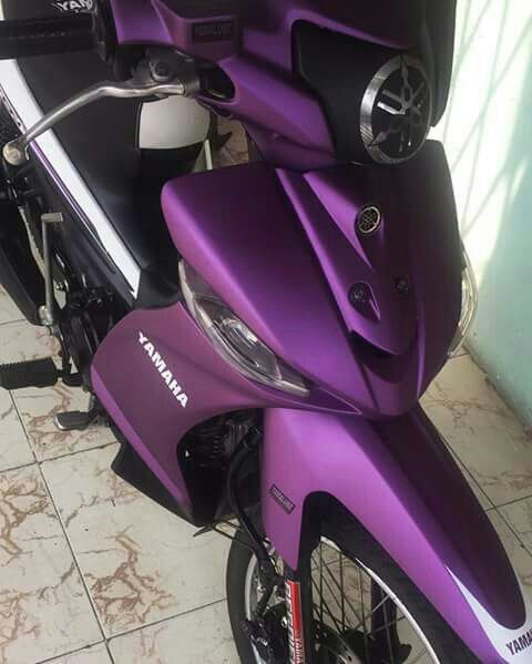 a purple motorcycle parked next to a wall on a tile floor in front of a building