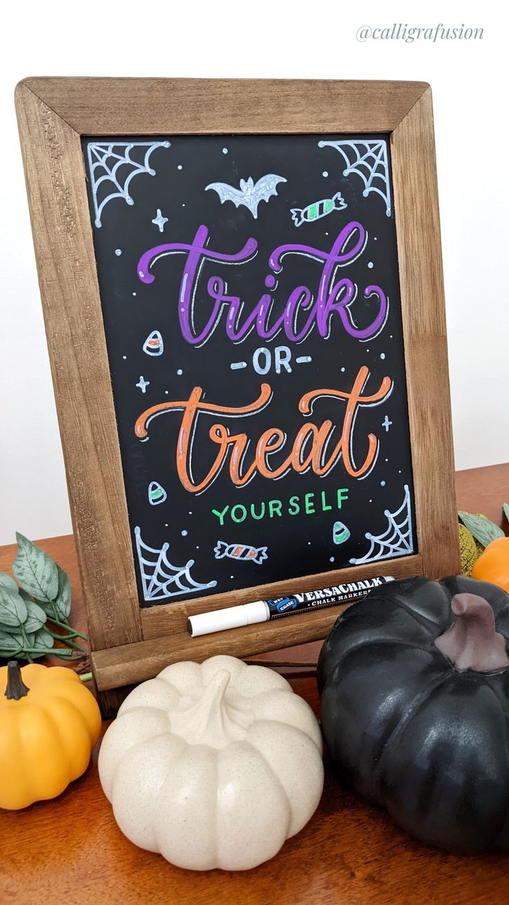 a chalkboard with trick or treat written on it next to pumpkins and gourds