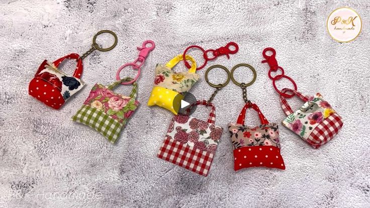 six small purses are lined up on a towel with one keychain in the middle