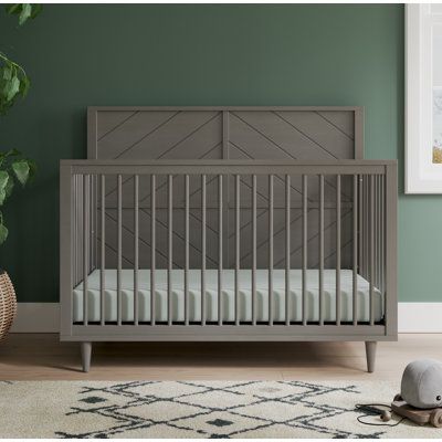 a baby crib in a green room with a rug and stuffed animal on the floor