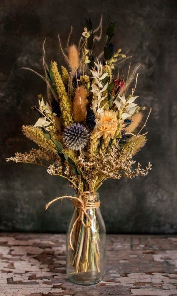 a vase filled with dried flowers on top of a table