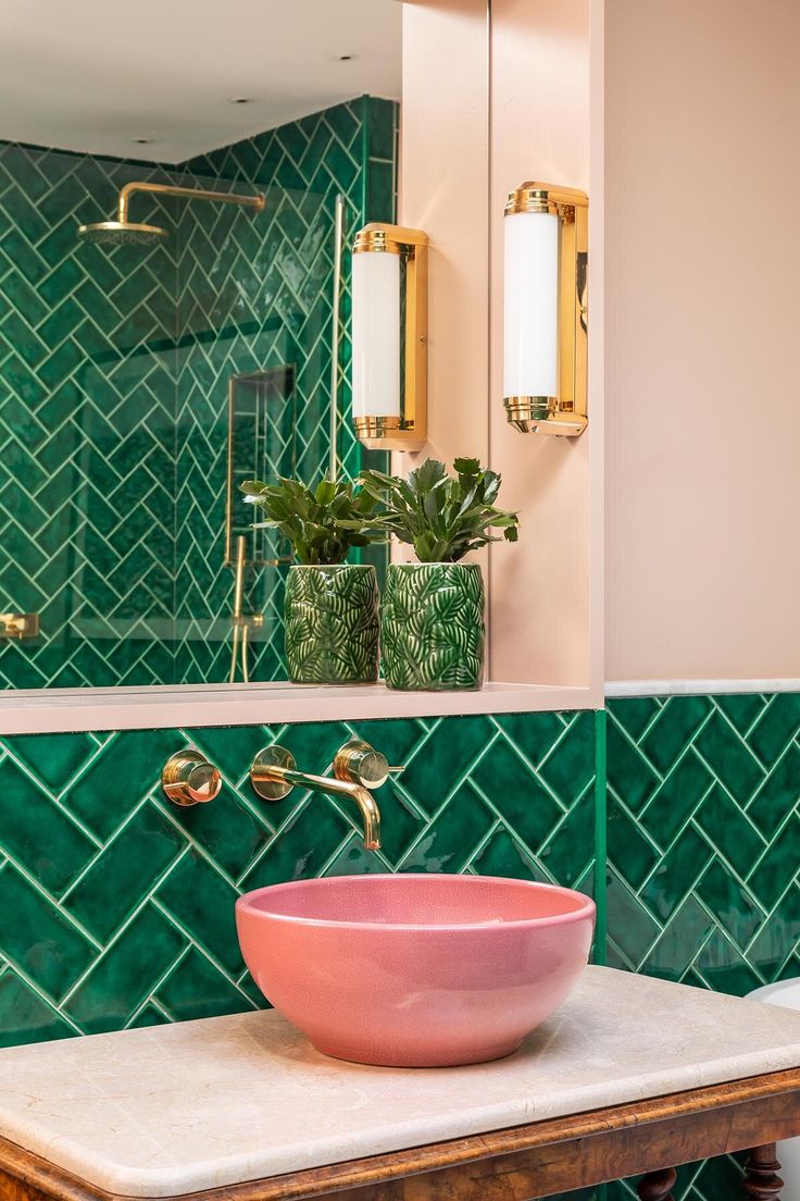 a bathroom with green tiles and a pink bowl sink