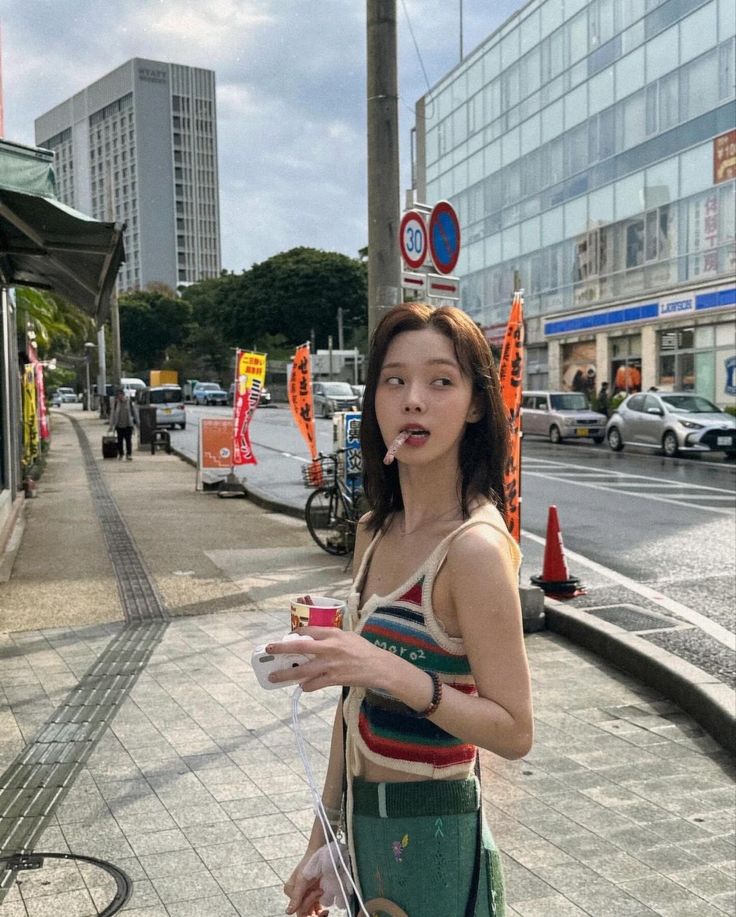 a woman standing on the side walk holding a bag