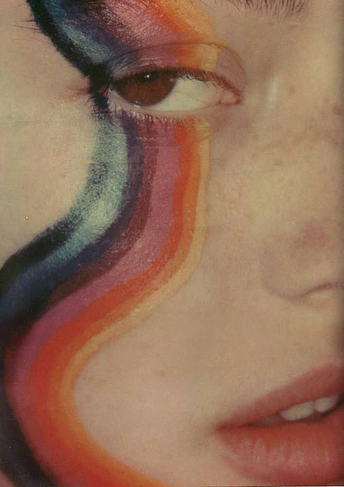 a woman's face with multicolored lines painted on her cheek and eyes