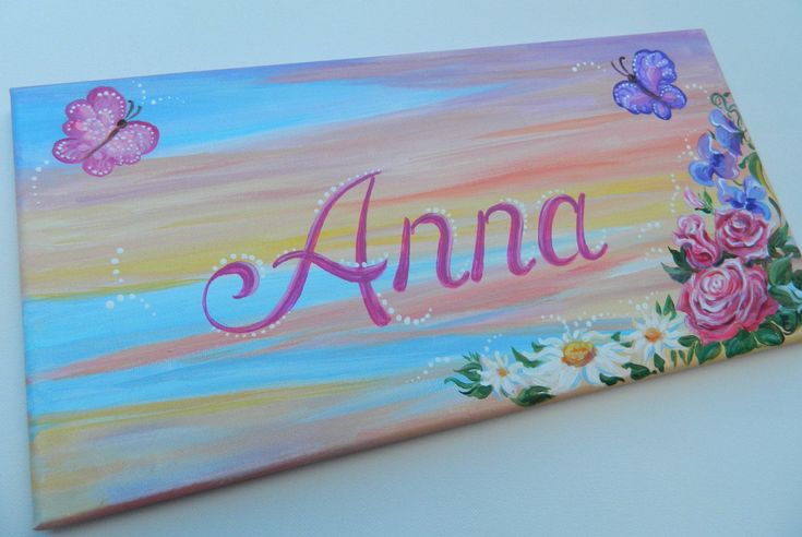 a painted name sign with flowers and butterflies on the bottom that says,'anna '