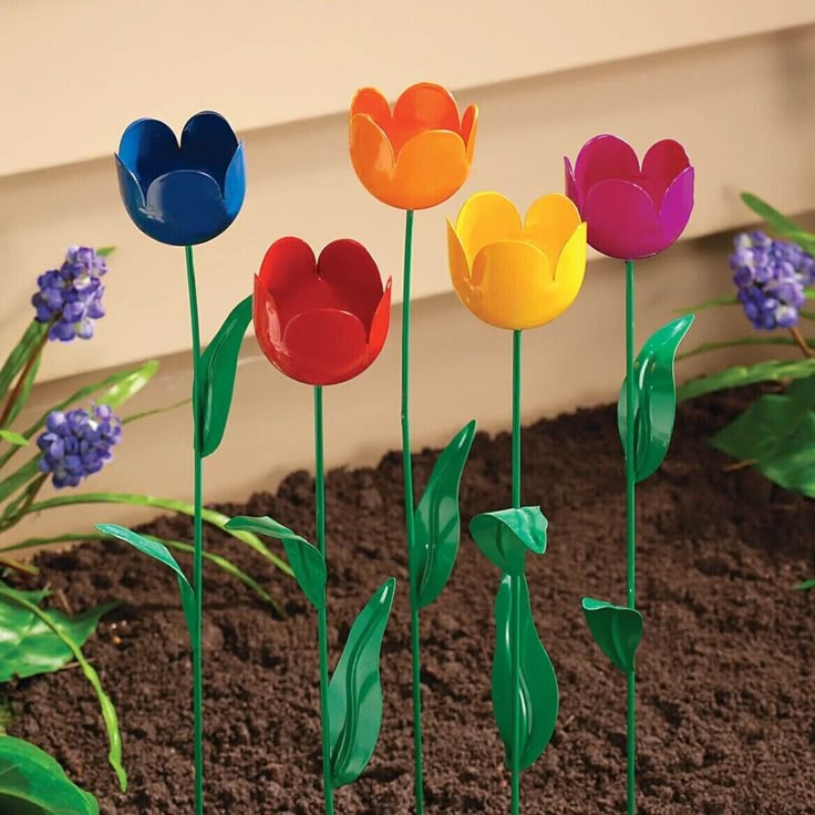 four colorful plastic flowers in the dirt