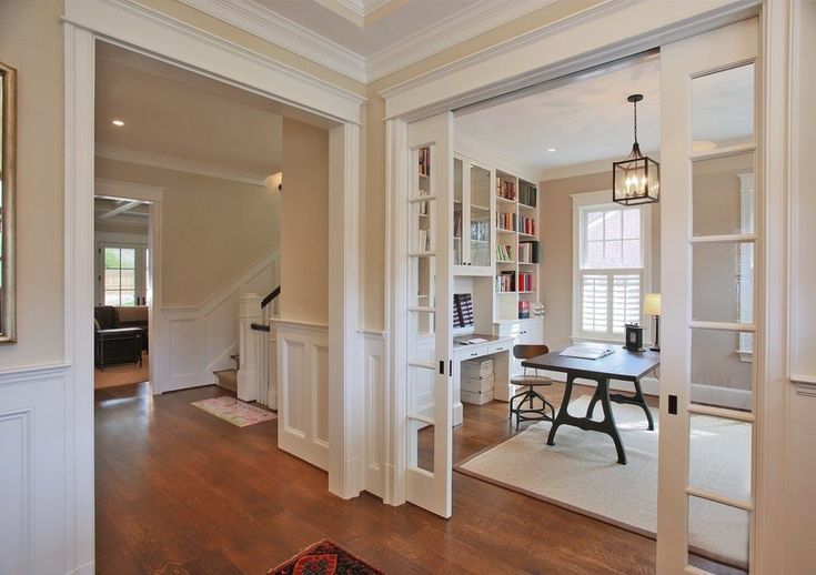 a home office with built in bookshelves, desk and stairs leading up to the second floor