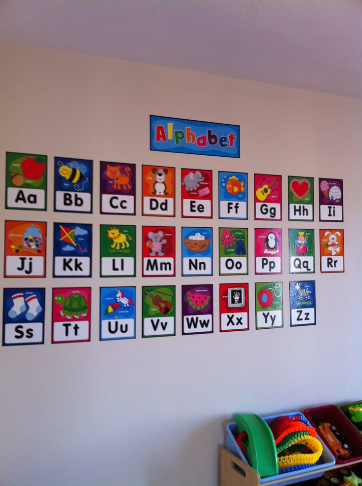 a child's playroom with alphabets on the wall and toys in bins