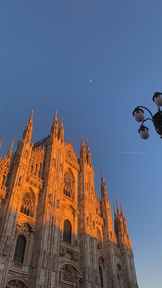 the sun is shining on an ornate building with street lights and lamps in front of it