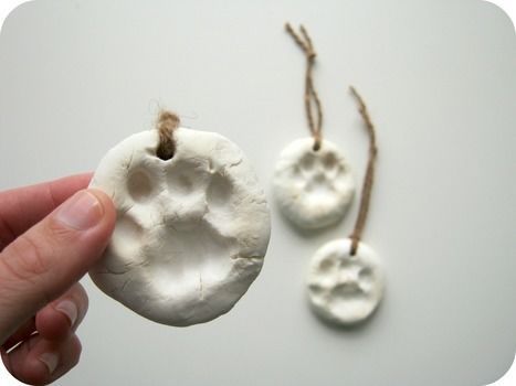 a hand holding a piece of white clay next to two small pieces of paper with twine on them