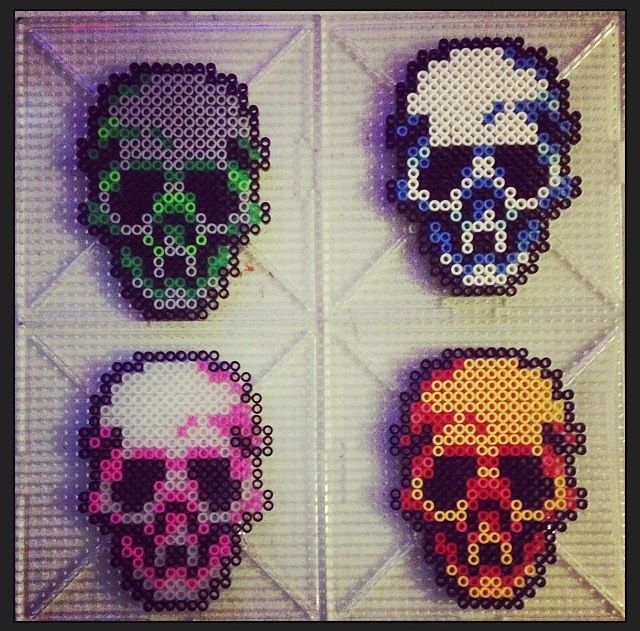 four pixelated skull heads are displayed on a white tile wall, each with different colors and sizes