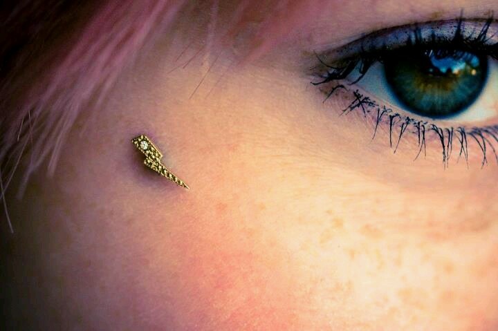 a close up of a person's eye with a gold nose pin