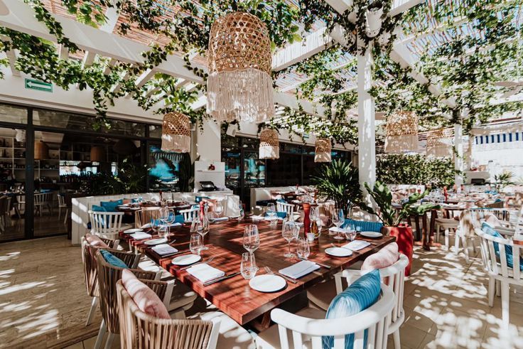 an outdoor dining area with tables, chairs and chandelier hanging from the ceiling