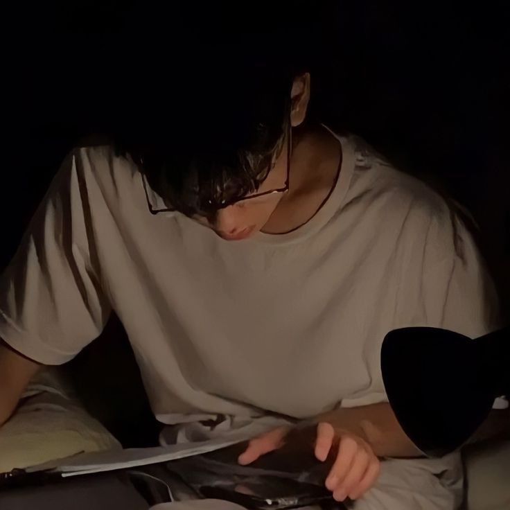 a young man reading a book in the dark