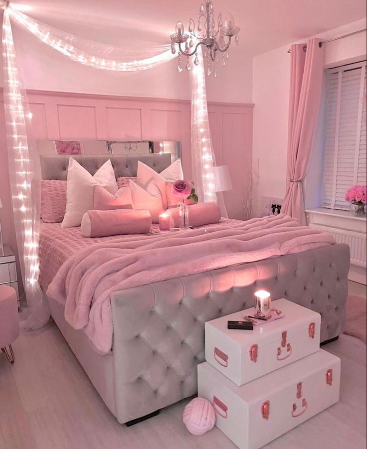 a bedroom with pink and white decor in the corner is lit up by fairy lights