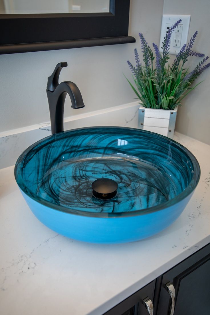 a blue bowl sink sitting on top of a white counter next to a black faucet