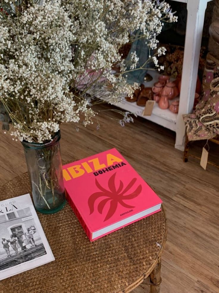 a vase filled with baby's breath sitting on top of a table next to a book