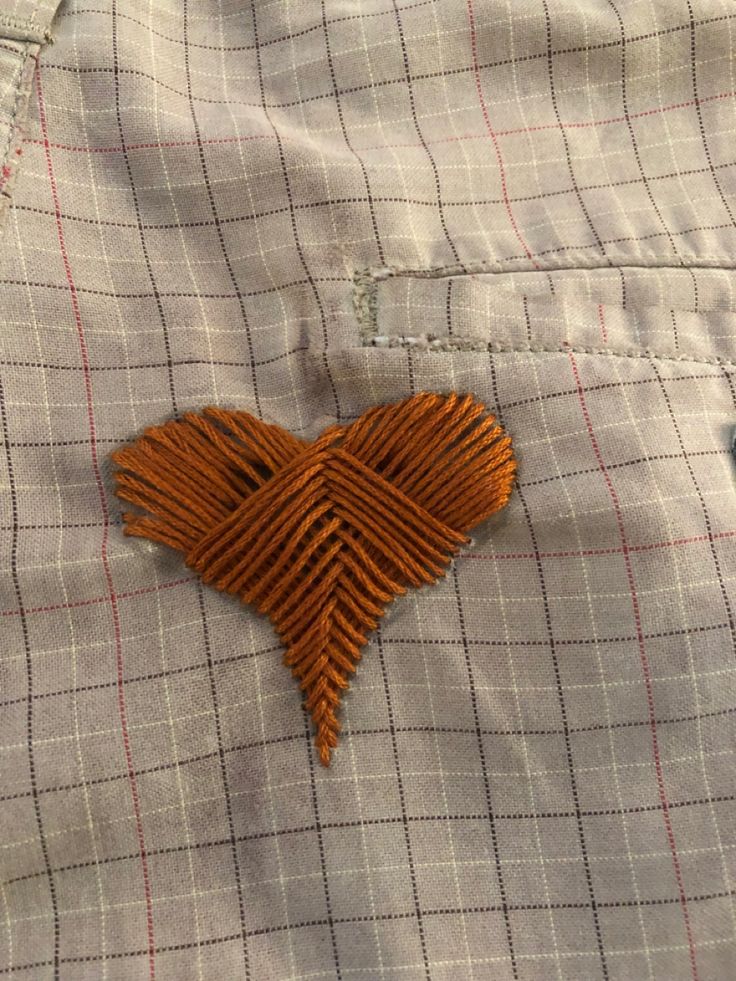 a close up of a button on a dress shirt with a heart shaped brooch