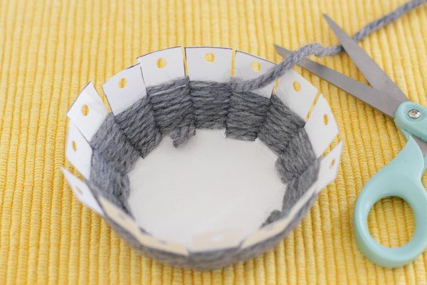 a pair of scissors sitting on top of a table next to a bowl with yarn