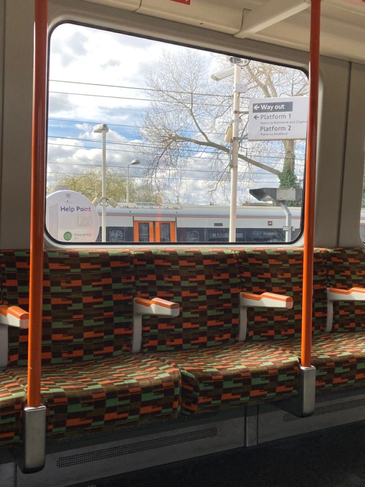 the inside of a train with seats and railings on both sides, looking out window