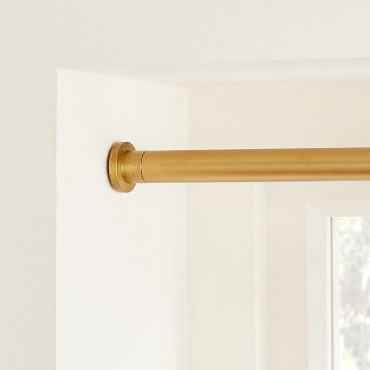 a curtain rod is hanging in front of a window with white walls and windowsills