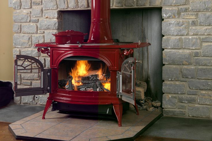 a red stove in a living room next to a fire place