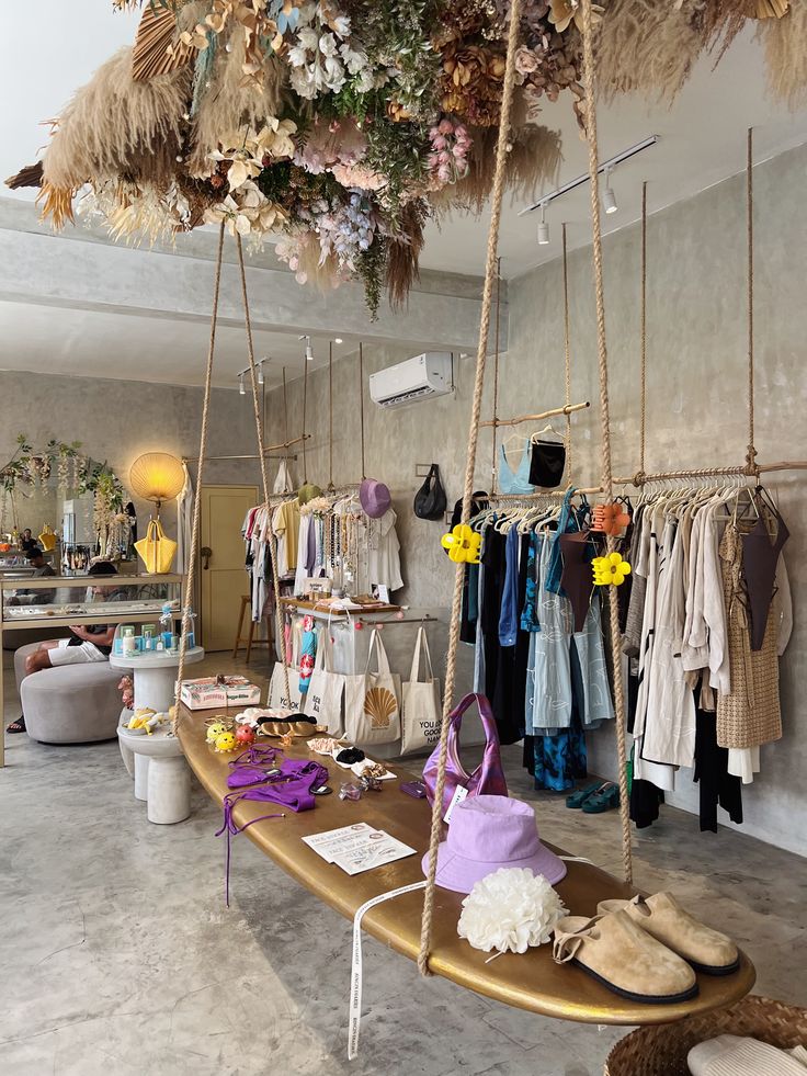 a surfboard is on display in a store with lots of clothes hanging from the ceiling