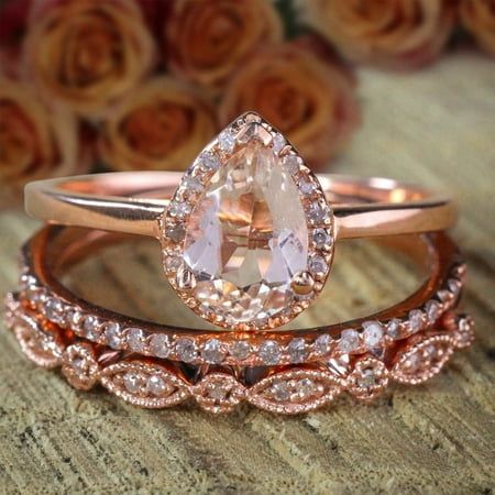 three rose gold wedding rings with an oval cut diamond in the center, and a pear shaped morganite on each band