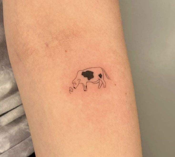 a small cow tattoo on the arm