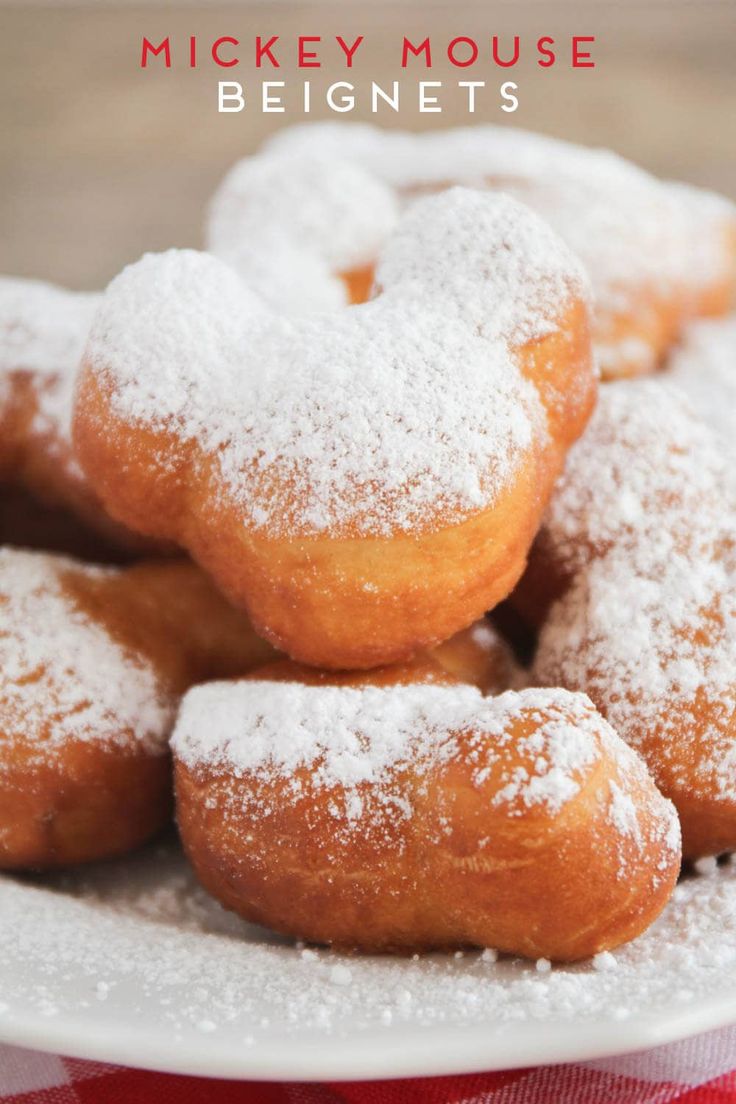 powdered sugar covered doughnuts on a plate with red and white checkered table cloth