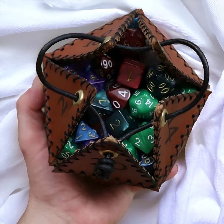 a hand holding a leather dice bag filled with colorful dice