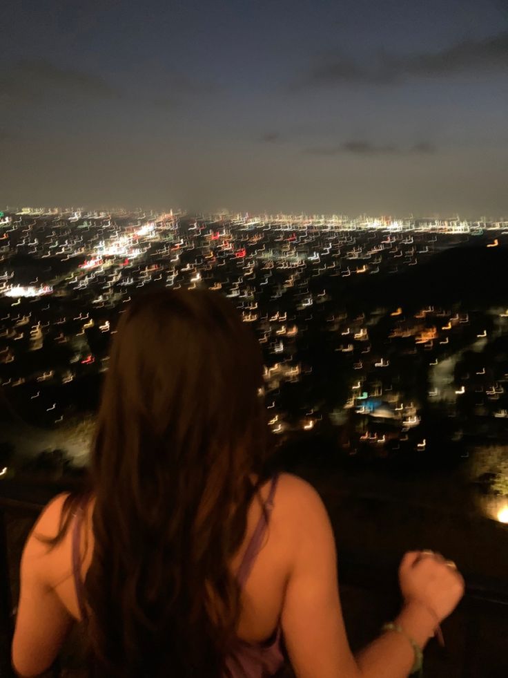 a woman looking out over the city at night