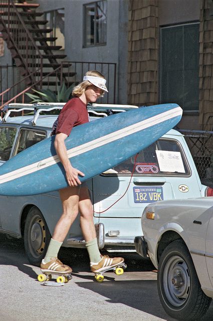 a man walking down the street with a surfboard strapped to his back while wearing sandals