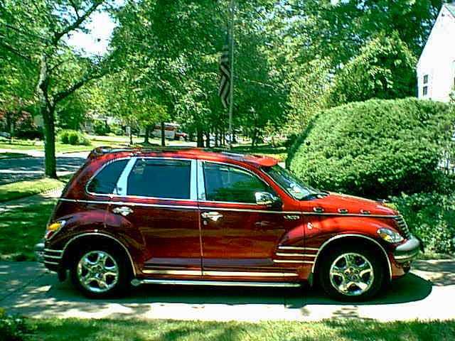 a red car is parked on the side of the road in front of some bushes