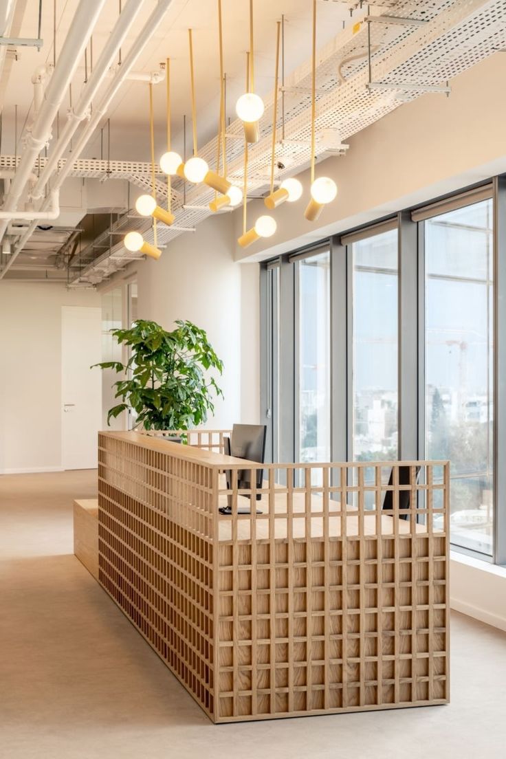 an office with large windows and a wooden desk in front of a plant on the wall