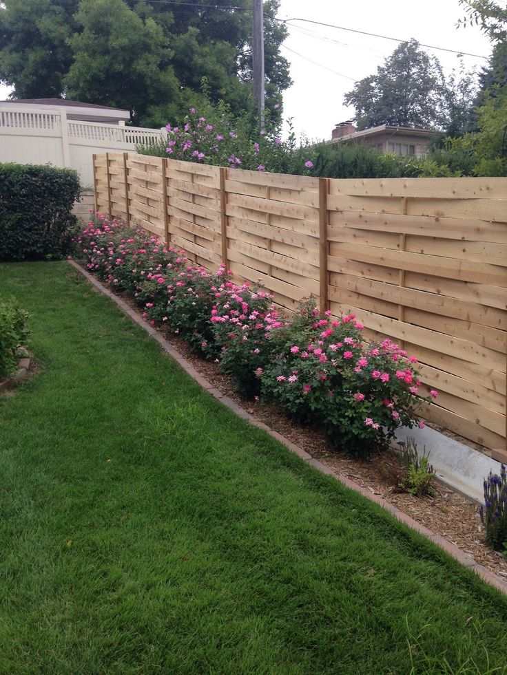 a wooden fence with pink flowers growing on the top and bottom, along side it