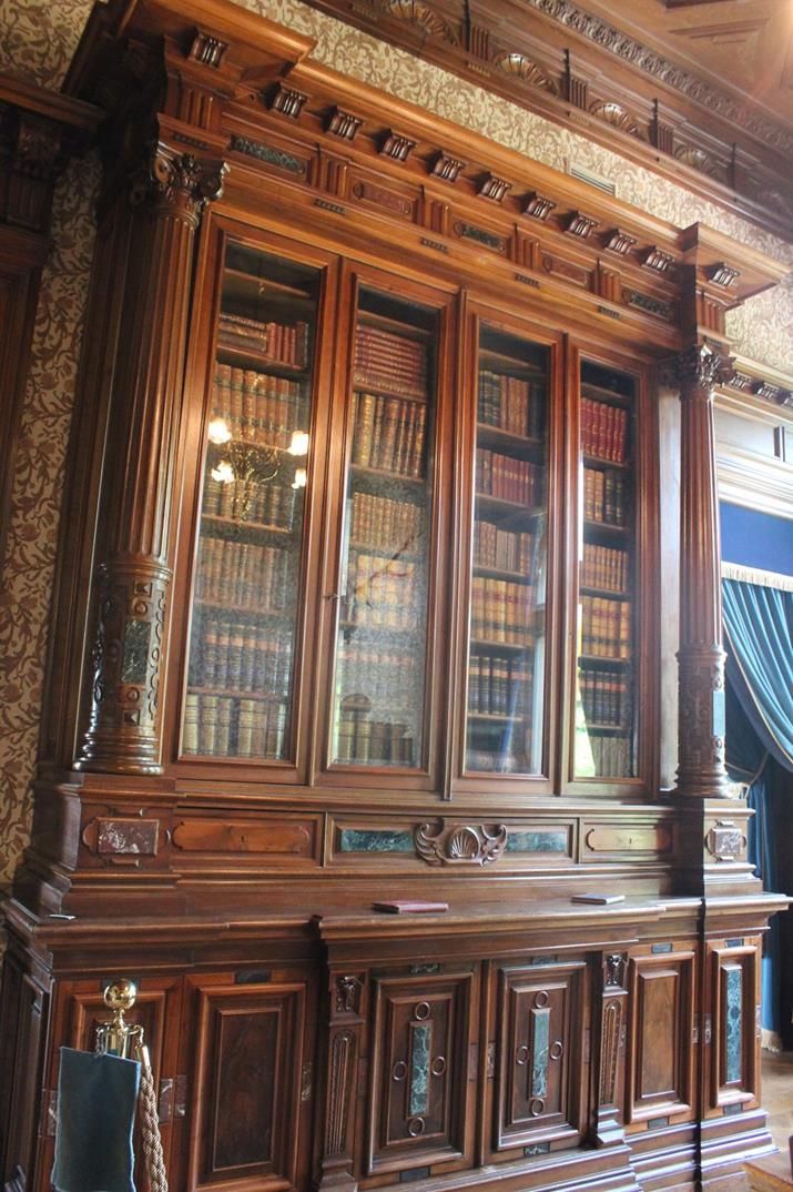 an old wooden bookcase with many books on it's shelves in a room