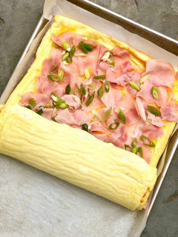 a square pizza with ham and cheese in a pan on the counter top, ready to go into the oven