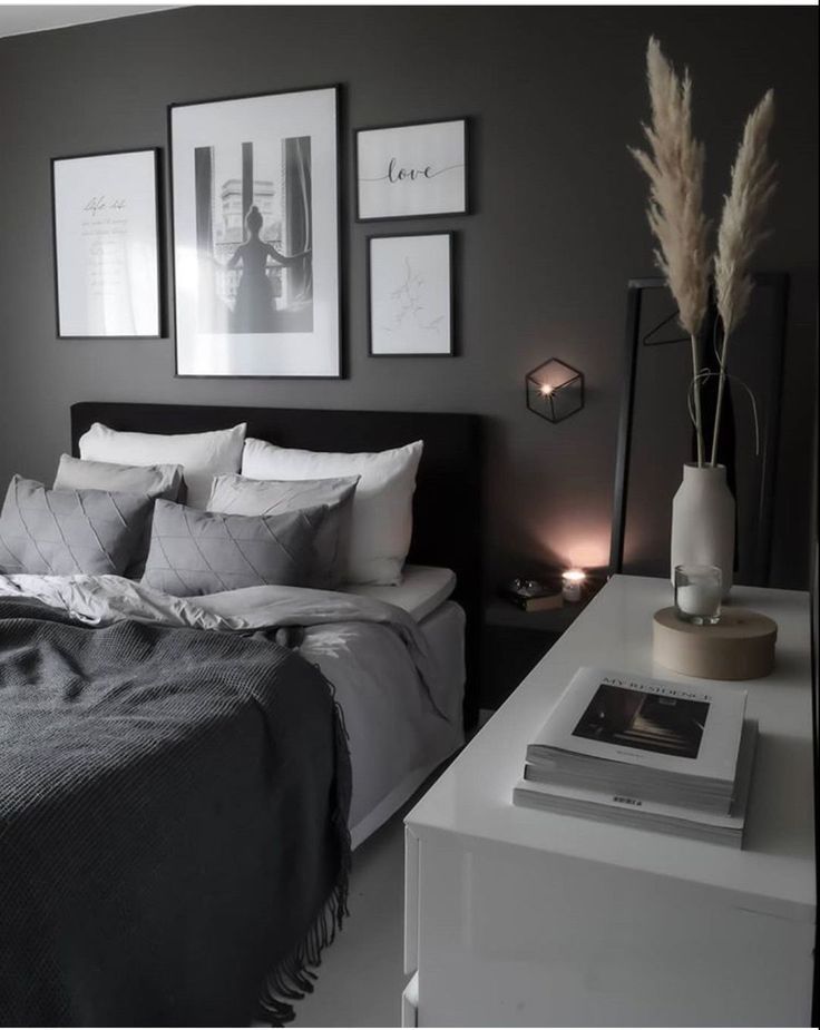 a bedroom with gray walls and pictures on the wall above the bed, along with candles