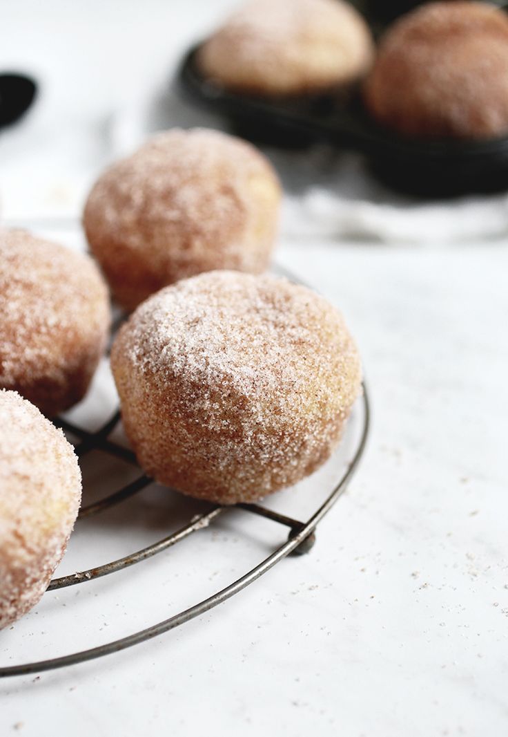 powdered sugar donuts on a wire rack with other pastries in the background