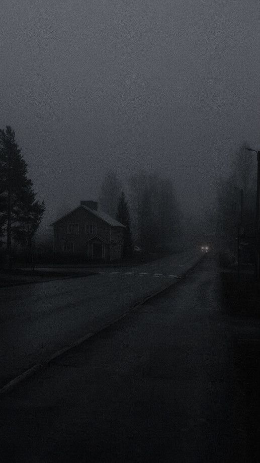 a dark street with houses and trees in the background on a foggy day at night