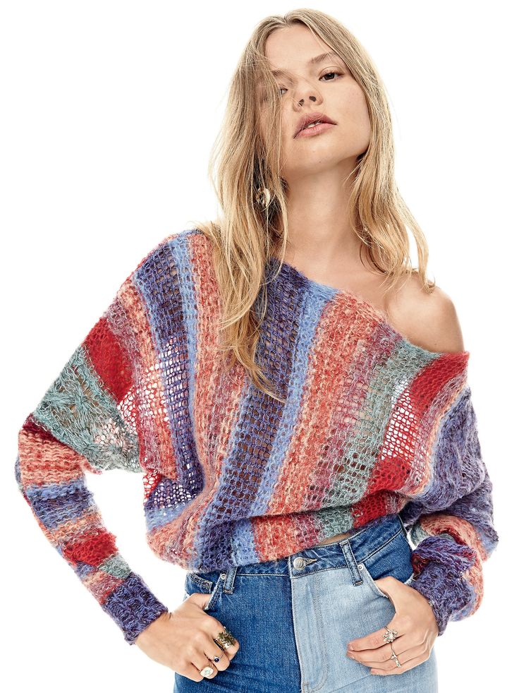 a woman is wearing a multicolored sweater and denim shorts with her hands on her hips