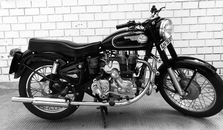 a black motorcycle parked in front of a brick wall