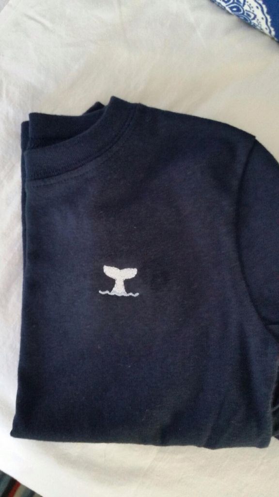 an image of a t - shirt with a whale on it sitting on a bed