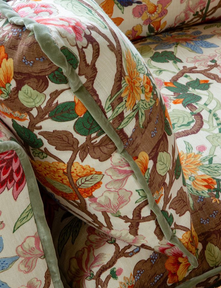 an upholstered chair with floral fabric and green ribbon on the armrests