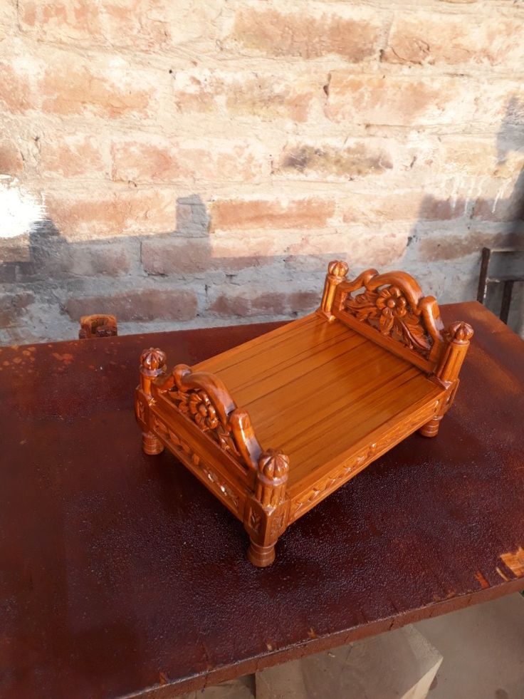 a wooden bed sitting on top of a brown table next to a brick wall in an old building