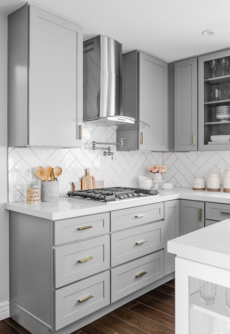 a kitchen with gray cabinets and white counter tops