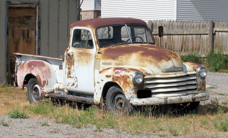 an old rusted truck parked in front of a building